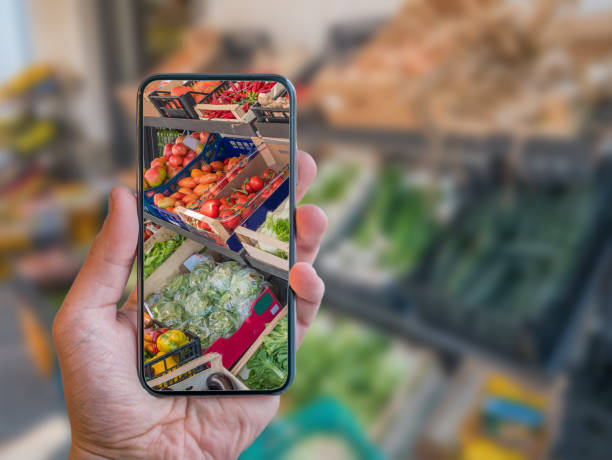 istock Augmented reality grocery shopping mobile app. Hand is holding cellphone with AR application scanning vegetables at food market. 1148608353