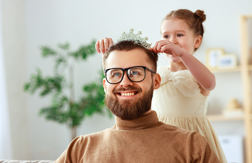 happy father's day! child daughter in crown does makeup to daddy and laughs