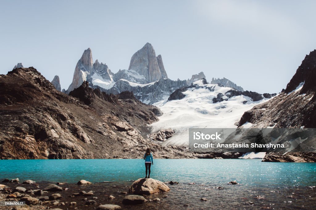 Woman looking at Fitz Roy mountain and turquoise lagoon in El Chalten, Argentina Young woman enjoying a day at Argentinian Patagonia - hiking to Fitz Roy mountain and lagoon De Los Tres during bright warm summer day Argentina Stock Photo