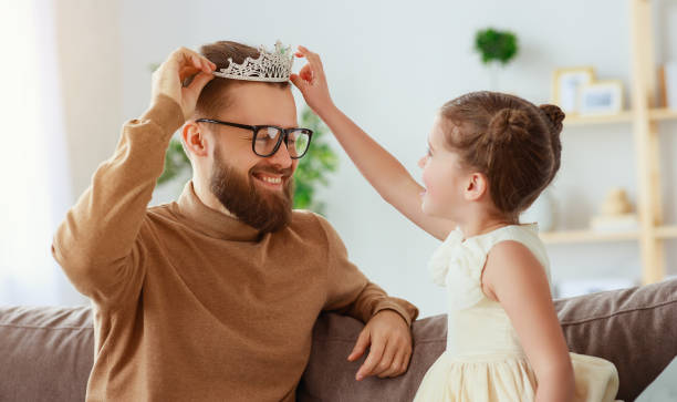 istock happy father's day! child daughter in crown does makeup to daddy 1148610715
