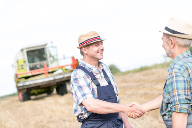 istock Farmers shaking hands while standing on field at farm 1148610764