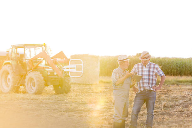 istock Farmers discussing over digital tablet while standing against harvester at farm 1148610882