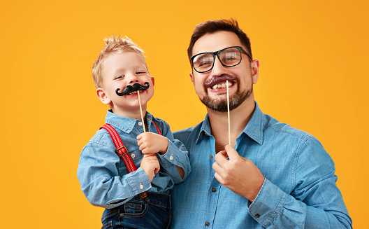 Feliz día de padre! padre gracioso e hijo con bigote jugando con el fondo amarillo photo