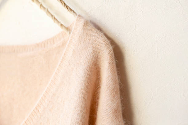istock light pink sweater hanging on clothes hanger on white background. 1148611096