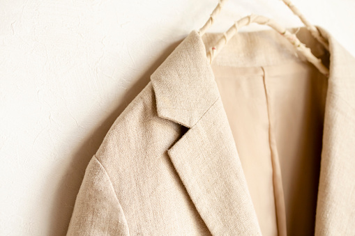 beige jacket hanging on clothes hanger on white background.close up.