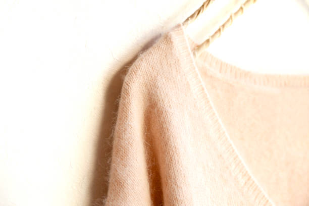 istock light pink sweater hanging on clothes hanger on white background. 1148611244