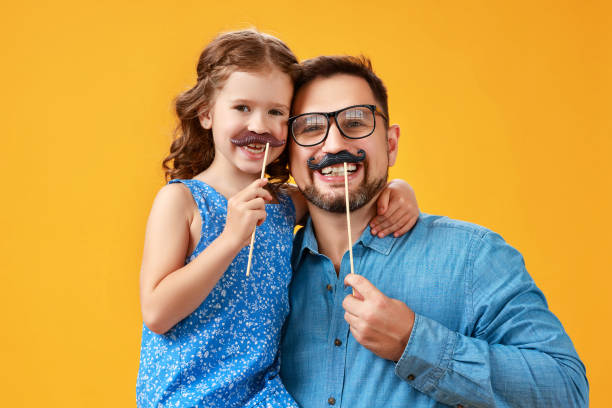 happy father's day! funny dad and daughter with mustache fooling around on yellow background happy father's day! funny dad and daughter with mustache fooling around on colored yellow background happy fathers day funny stock pictures, royalty-free photos & images