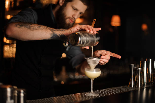 istock Bartender adds sour mix in alcohol cocktail using shaker and sieve 1148615549