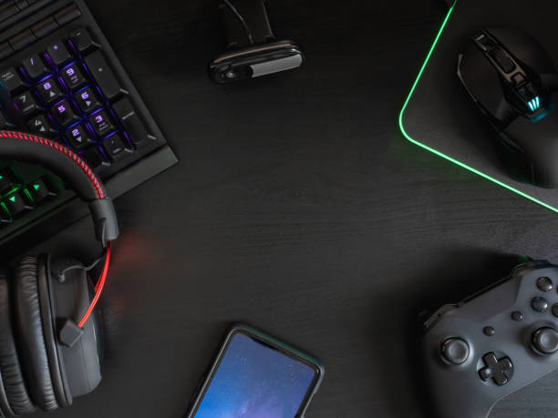 istock gamer workspace concept, top view a gaming gear, mouse, keyboard, joystick, headset, mobile joystick and mouse pad on black table background with RGB color. 1148617267