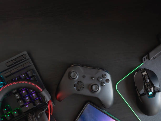 istock gamer workspace concept, top view a gaming gear, mouse, keyboard, joystick, headset, mobile joystick and mouse pad on black table background with RGB color. 1148617421
