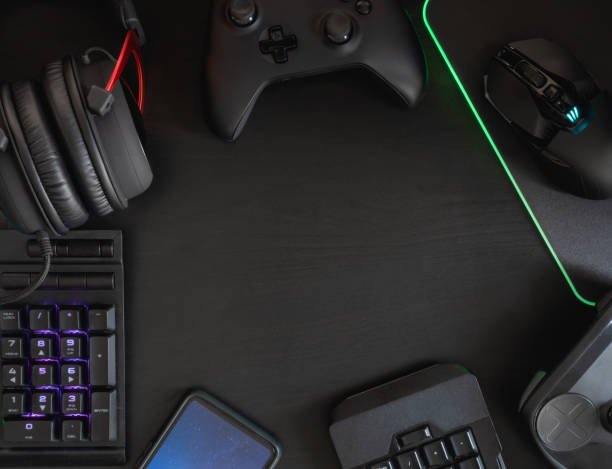 istock gamer workspace concept, top view a gaming gear, mouse, keyboard, joystick, headset, mobile joystick and mouse pad on black table background with RGB color. 1148617499