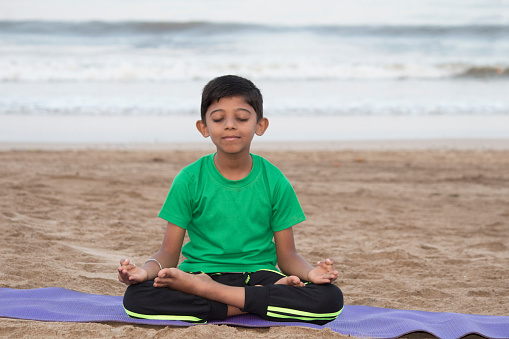 Boy practicing meditation on the beach