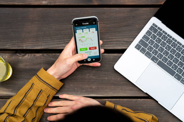 Above angle view of a young man using a trading app