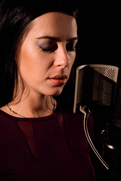 istock Young woman singer in front of microphone. 1148624244