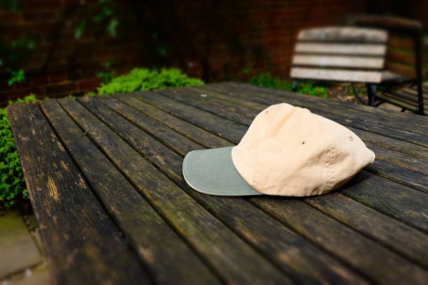 Berkshire, England - May 4, 2019: this cream and grey coloured baseball cap has been forgotton by its owner on a table surrounded by chairs.