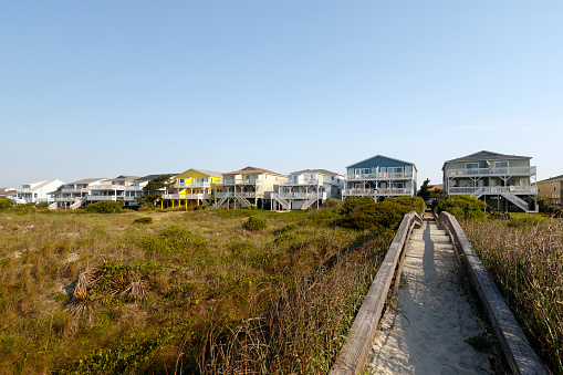 Beach houses across the green sand dunes with a long wooden walkway, Sunset Beach, North Carolina
