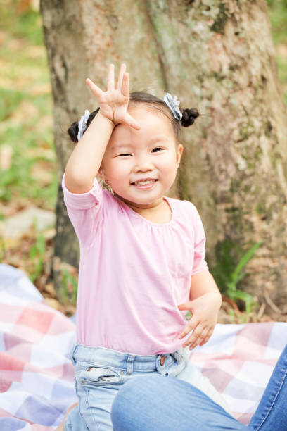 Portrait of cheerful little Asian girl waving with her hand and saying good bye