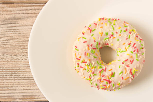 istock Fresh glazed donut with colorful sprinkles on a white plate. 1148641225