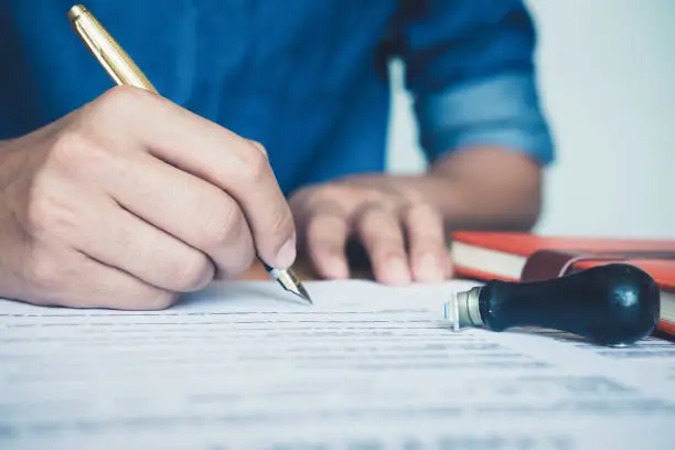 Photo of Close up business man reaching out sheet with contract agreement proposing to sign.Full and accurate details, individual who owns the business sign personally,director of the company, solicitor.