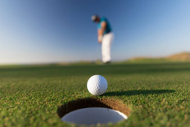 balle de golf entrant dans le trou après un coup réussi-fermer-liens golf - sports flag flag shadow golf flag photos et images de collection