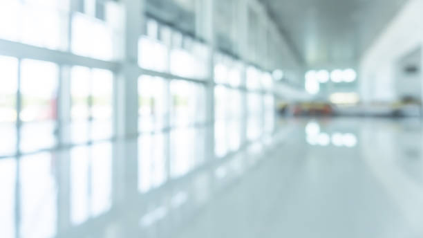 office building lobby hall blur background or blurry school hallway corridor interior view looking toward empty entrance, glass curtain wall and floor with exterior light illumination - office window indoors contemporary imagens e fotografias de stock