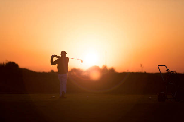 ゴルフ選手 shoting ボール-サンセットタイム-リンクスゴルフ - sports flag flag shadow golf flag ストックフォトと画像