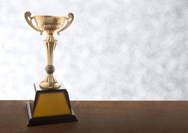 istock Gold trophy on wooden table on bokeh background. Winning awards with copy space. 1148649286