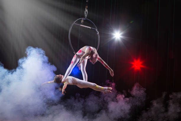 actuación de actriz de circo acróbata. dos chicas realizan elementos acrobáticos en el anillo de aire. - acróbata circo fotografías e imágenes de stock