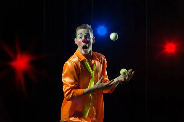 Circus clown performs number. Clown man juggles