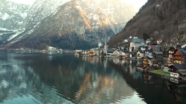 Hallstatt is a small town in the district of Gmunden, in the Austrian state of Upper Austria. Situated between the southwestern shore of Hallstätter See and the steep slopes of the Dachstein massif, the town lies in Salzkammergut region. Hallstatt is known for its production of salt, dating back to prehistoric times, and gave its name to the Hallstatt culture, the archaeological culture linked to Proto-Celtic and early Celtic people of the Early Iron Age in Europe. Small alpine village in the glaciers valley by the lake. Drone footage, aerial views, nature in winter time.