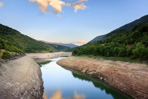 Photo of View of reflective water of Zavoj lake from a bridge with cloud from the sky reflecting in the water surface