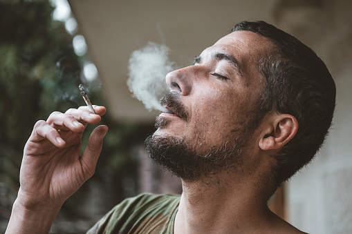 Bearded man smoking a marijuana joint