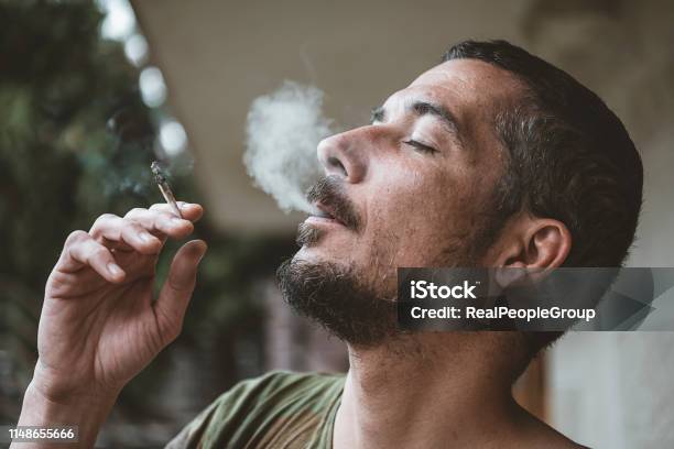 Bearded Man Smoking A Marijuana Joint Stock Photo - Download Image Now - Smoking - Activity, Marijuana - Herbal Cannabis, Smoke - Physical Structure