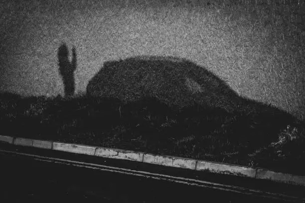 Photo of Silhouette of a teenager and a car cast by the setting sun on a construction hoarding