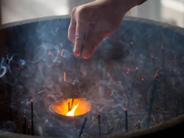 Incense stick lit by flame through smoke, Japan