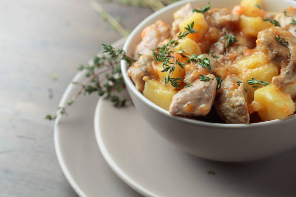 Irish stew sprinkled with green thyme.  Meat stewed with potatoes, carrots and spices on wooden background.