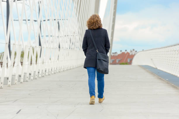 istock Woman walking away across a pedestrian bridge 1148666961