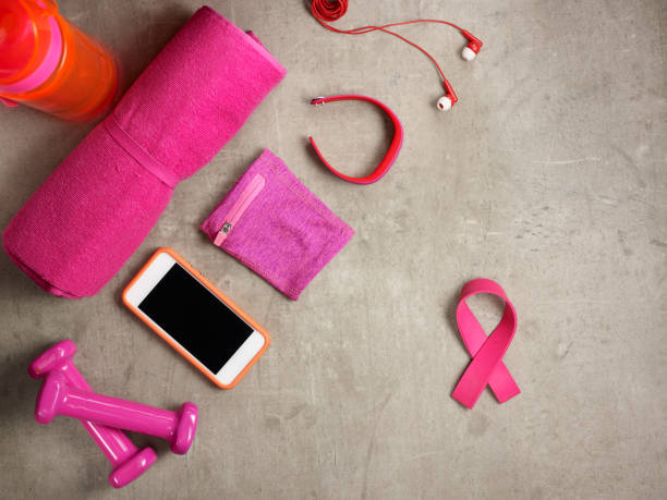 dumbbells, towel, smartphone and pink ribbon shaped elastic band stock photo