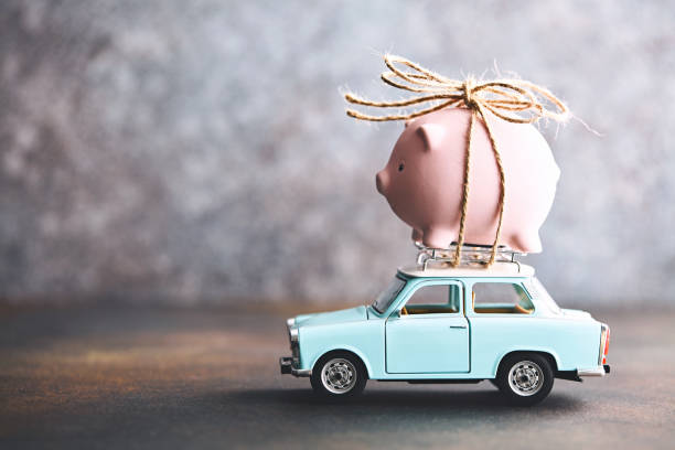 Little pink piggy bank tied to the top of an old car Little pink piggy bank tied to the top of an old car vehicle accessory stock pictures, royalty-free photos & images