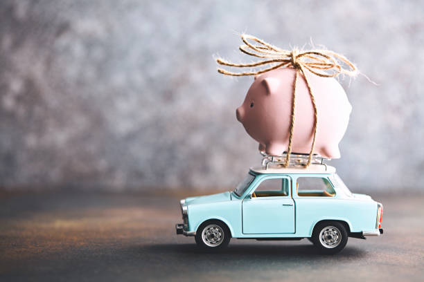 Little pink piggy bank tied to the top of an old car Little pink piggy bank tied to the top of an old car cash in transit vehicle stock pictures, royalty-free photos & images