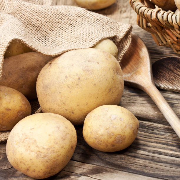 istock Potatoes and herbs with spoons against wooden background 1148671782