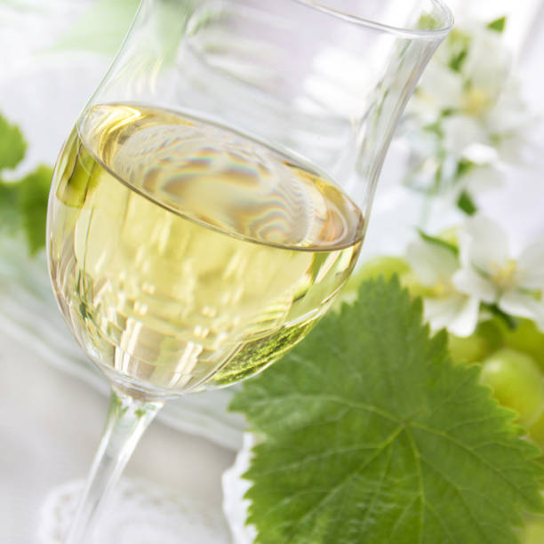 istock White wine and wine leaves on green background 1148671973