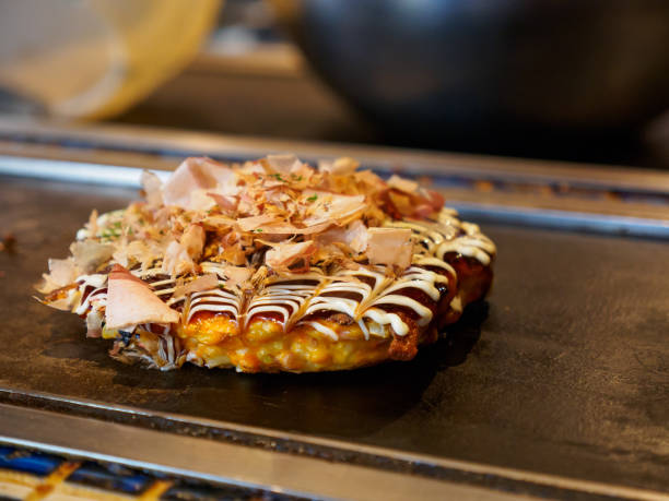 okonomiyaki sulla griglia teppan, namba, osaka, giappone - okonomiyaki foto e immagini stock
