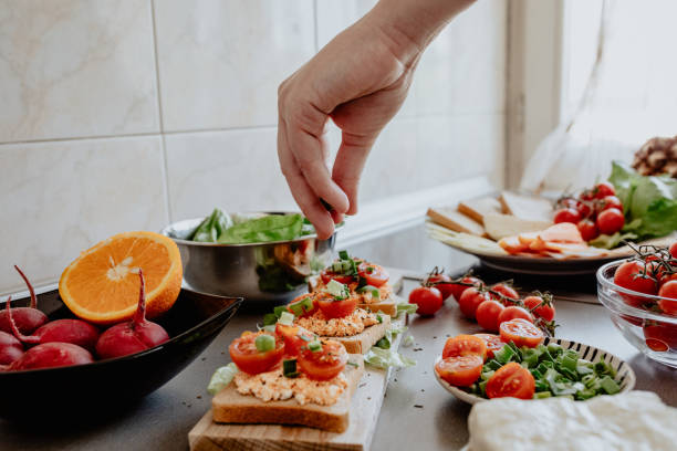 Seasoning tasty bruscheta in the kitchen Seasoning tasty vegetarian bruschetta with basil and garlic cook prepared delicious gourmet canapé starters stock pictures, royalty-free photos & images