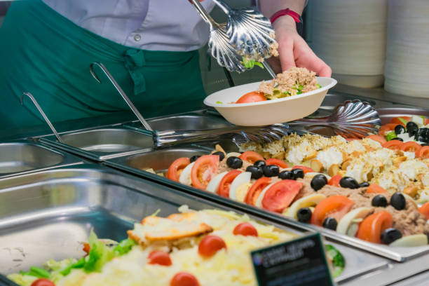 istock buffet self-service food display human hand take plate and put a salad. full lunch service station 1148691155