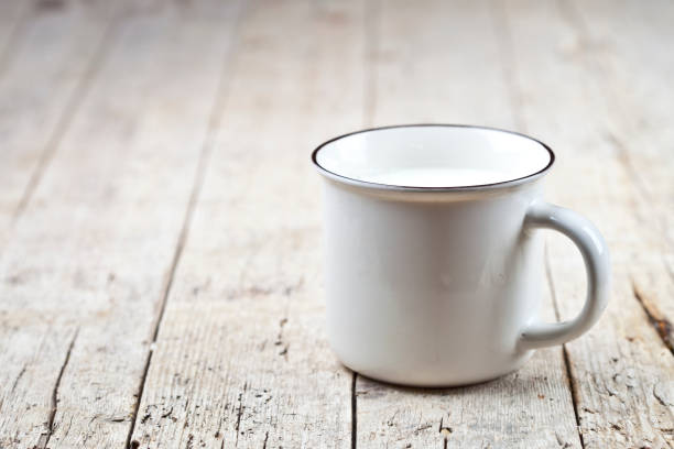 Fresh milk on white ceramic cup on rustic wooden table background. stock photo