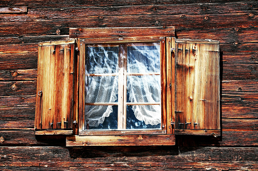 Windows with curtains and shutters on an old wooden house