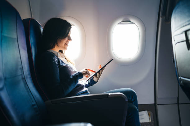 el uso de una tableta digital en un avión - silla al lado de la ventana fotografías e imágenes de stock