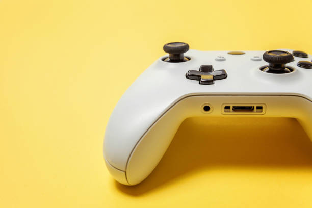 istock White joystick on yellow background. Computer gaming competition videogame control confrontation concept 1148701528