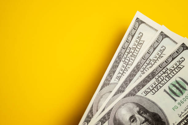 istock Dollar cash, banknotes on the yellow background. 1148702324